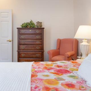 Cozy bedroom with a colorful bedspread and an elegant wooden dresser.