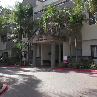 A residential apartment building with palm trees and a welcoming entrance.