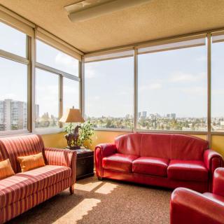 A cozy living room with red sofas and large windows offering a city view.