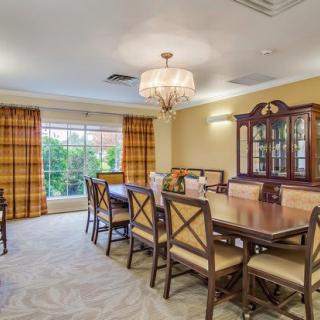 A spacious dining room with a large table, elegant chandelier, and classic furnishings.