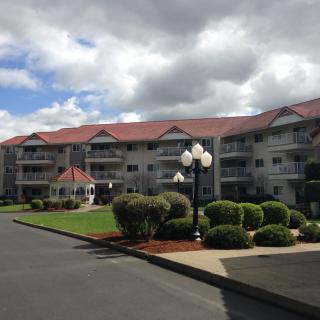 A residential building with landscaped gardens under a cloudy sky.