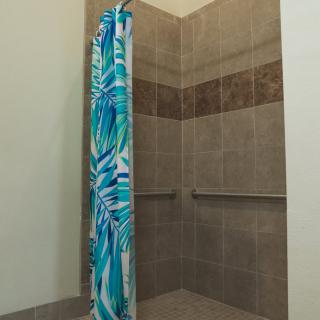 A tiled shower area with a colorful curtain in a bathroom.