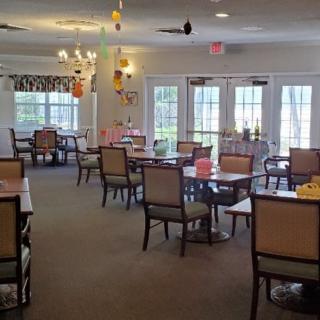 A cozy dining area with tables and chairs arranged neatly, featuring hanging decorations.