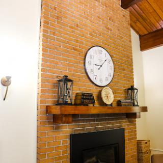 A cozy living room featuring a rustic brick wall with a clock and decorative lanterns above the fireplace.