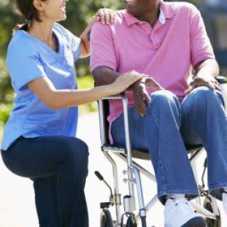 A caregiver assisting a person in a wheelchair outdoors.