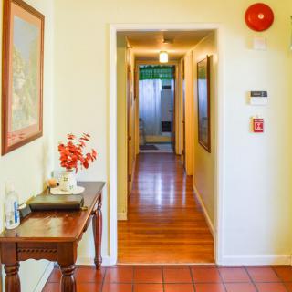 A well-lit hallway with wooden flooring and a decorative table on the side.