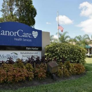 Sign for ManorCare Health Services surrounded by landscaping.