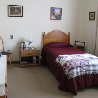 A tidy bedroom with a single bed, nightstand, and simple decor.