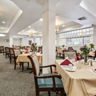 A spacious and elegantly designed dining area with neatly arranged tables and chairs, complemented by large windows.