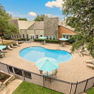 An aerial view of a residential swimming pool surrounded by patio furniture and trees.