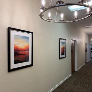 A hallway with framed artwork and modern lighting fixtures.