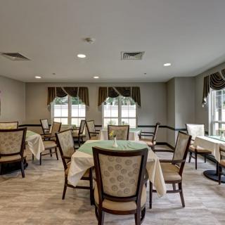 An elegant dining room with neatly arranged tables and cushioned chairs.