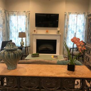 A cozy living room with a television mounted above a fireplace, surrounded by elegant decor and furniture.