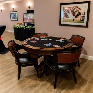 A poker table with chairs set up in a game room, featuring cards and chips ready for play.