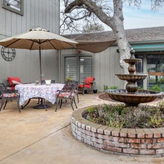 A cozy patio with a central fountain, surrounded by outdoor seating and a table under an umbrella.