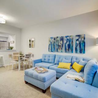 A contemporary living room featuring a stylish blue sectional sofa and vibrant artwork.