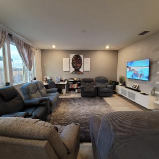 A cozy living room with a contemporary design featuring comfortable sofas, a large wall-mounted television, and elegant wall art.