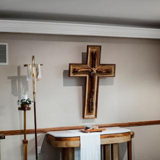 A beautifully crafted wooden cross hangs above an altar in a serene church setting.