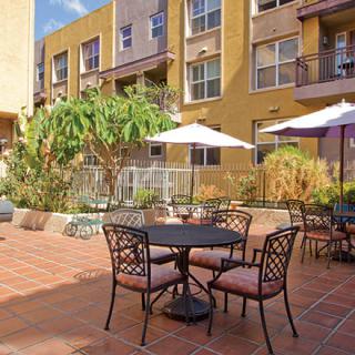 A sunny courtyard with patio furniture and umbrellas in an apartment complex.