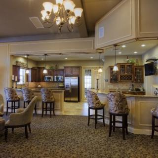 A spacious kitchen and dining area with bar stools, a chandelier, and a countertop.