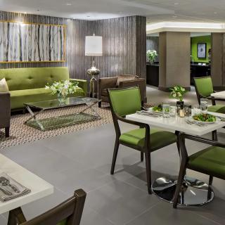 A modern restaurant interior featuring green-themed decor with neatly arranged tables and chairs.