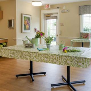 A bright community room with decorated tables and fresh flowers.