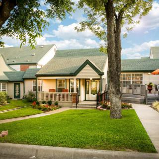 A charming suburban house with a well-maintained lawn and green roof.