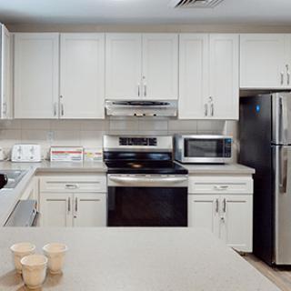 Modern kitchen with white cabinets and stainless steel appliances.
