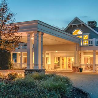 A beautifully lit building entrance in the evening with surrounding landscaping.