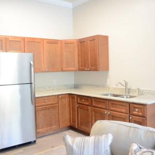 Modern apartment kitchen with wooden cabinets and stainless steel appliances.