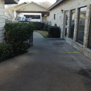 A pathway between two buildings with bushes lining the sides.