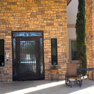 A welcoming entrance featuring a stylish black door and stone wall.