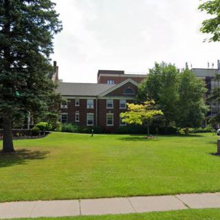 A residential building surrounded by a well-maintained lawn and trees.