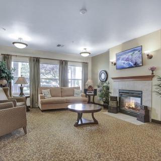 A cozy living room with a fireplace, sofa, and coffee table, featuring a television mounted on the wall.