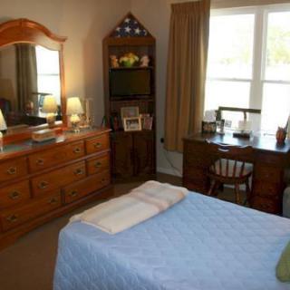 A cozy bedroom with a bed, dresser, and desk by the window.