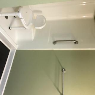 A compact bathroom with a sink, toilet, and grab bar.