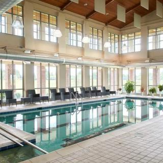 A luxurious indoor swimming pool surrounded by large windows and comfortable lounge chairs.