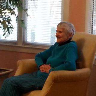 An elderly woman sitting comfortably in a chair near a window.