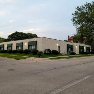 A modern commercial building with green accents, surrounded by well-maintained lawns.