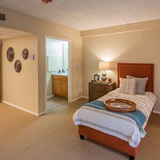 A cozy bedroom with a single bed, bedside lamp, and simple decor.