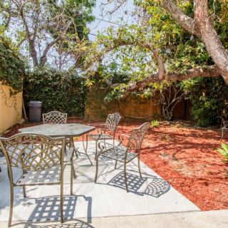 A peaceful backyard patio with metal furniture, surrounded by lush trees and garden space.
