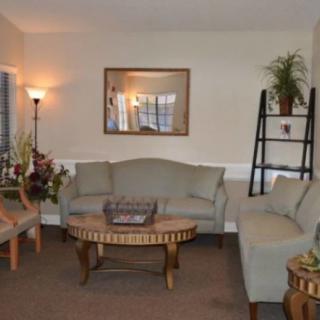 A cozy living room with comfortable seating, a wooden coffee table, and decorative elements such as plants and a mirror.