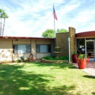 A mid-century modern house with a well-kept lawn and an American flag flying above.