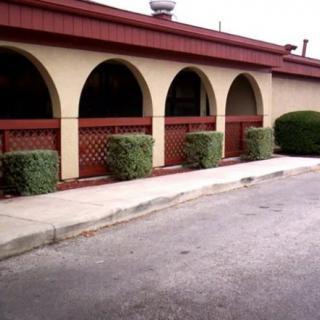 Exterior view of a restaurant with arched windows and landscaping.