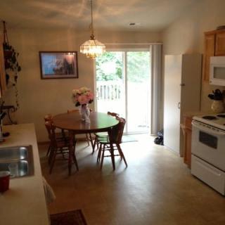 A cozy kitchen with a dining area, featuring a wooden table and chairs, and a large sliding door that lets in natural light.