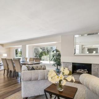 A spacious open-plan living and dining area with modern decor, featuring a cozy fireplace and ample natural light.
