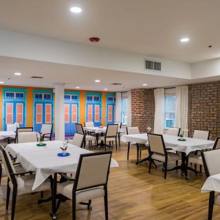 A modern dining room with neatly arranged tables and chairs, featuring a colorful decor and brick walls.
