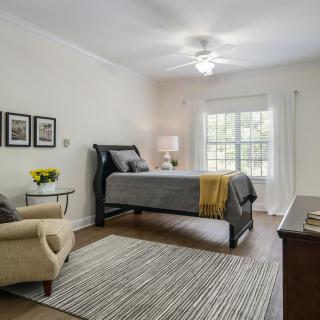 A cozy bedroom with stylish decor, including a bed, chair, rug, and artwork.