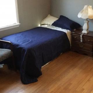 A cozy bedroom with a single bed, nightstand, and lamp.