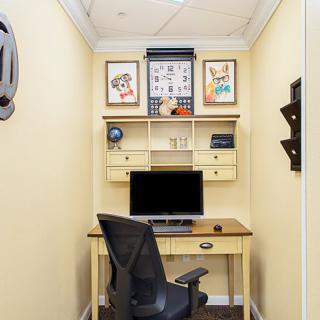 A compact home office setup with a desk, computer, and artwork on the walls.